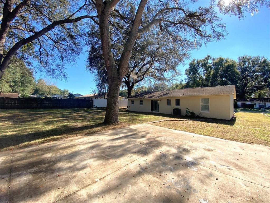 Fenced backyard with drive-thru gate and parking pad in front of accessory building