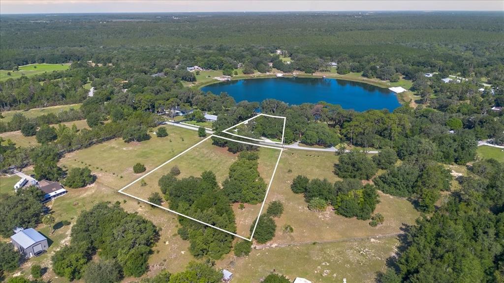 This aerial view highlights the property's generous footprint, private shoreline, mature trees, and picturesque setting.