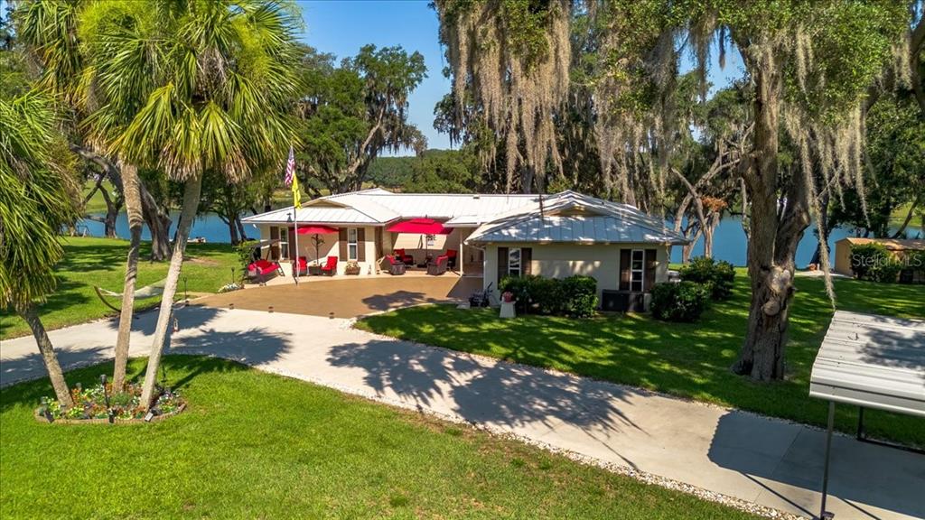 Nestled beneath towering live oaks with tranquil lake views, this beautifully maintained home welcomes you with an expansive circular driveway, oversized two-car garage, and a charming outdoor living space perfect for morning coffee or evening sunsets.
