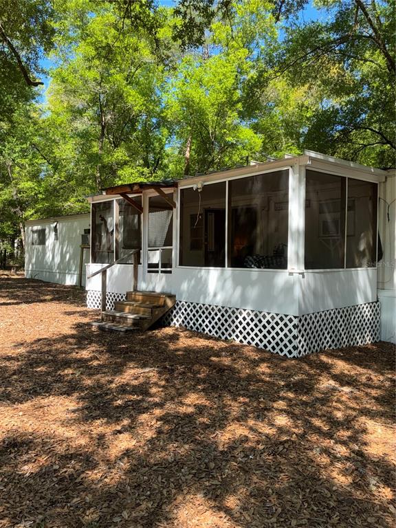 The front of the house, with fully screened in porch, enclosing the front door.