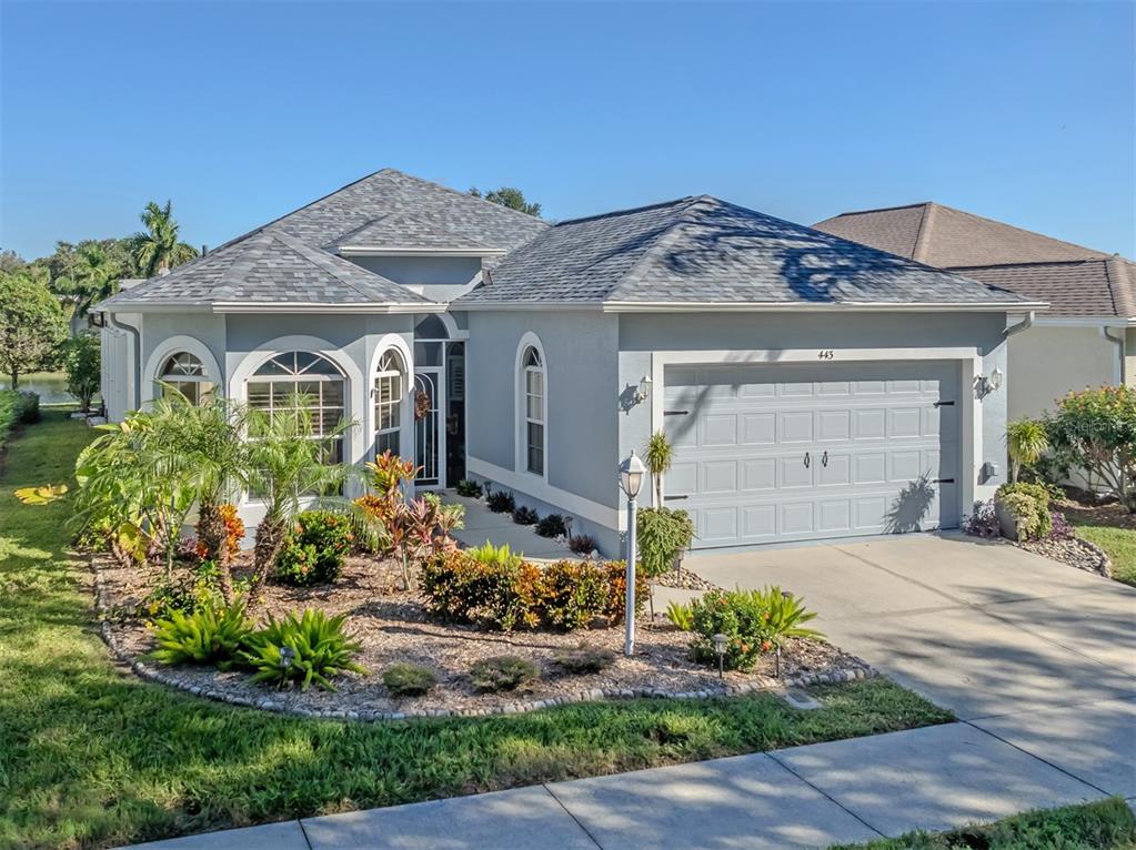 Beautiful curb appeal welcomes you home, featuring a charming bay window, lush mature landscaping, and a lovely glimpse of the peaceful lake beyond!