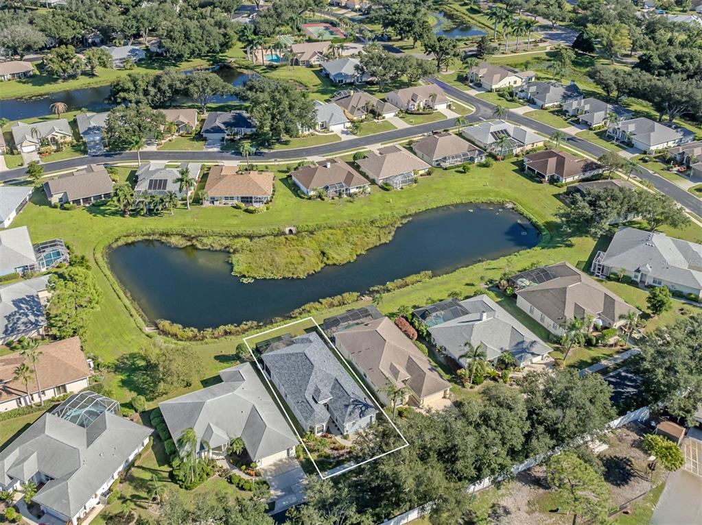 A bird’s-eye view of this lovely neighborhood, showcasing the home's beautiful setting, sparkling lake, and picturesque surroundings in the Isles of Chestnut Creek!