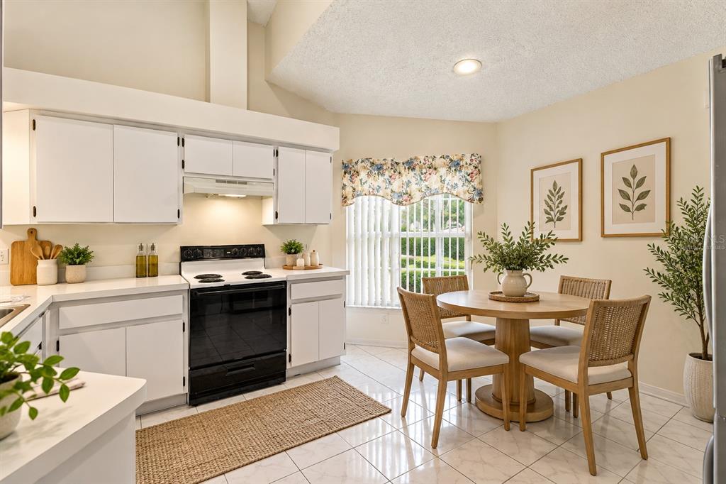 Virtually staged kitchen featuring an eat-in breakfast nook and tile flooring.