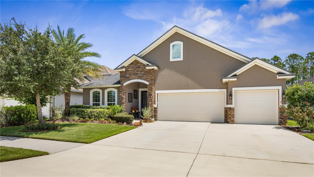 Picture yourself pulling up to this beautifully maintained home each day—lush landscaping, warm stone accents, and a welcoming tiled entry make coming home feel good from the very start.