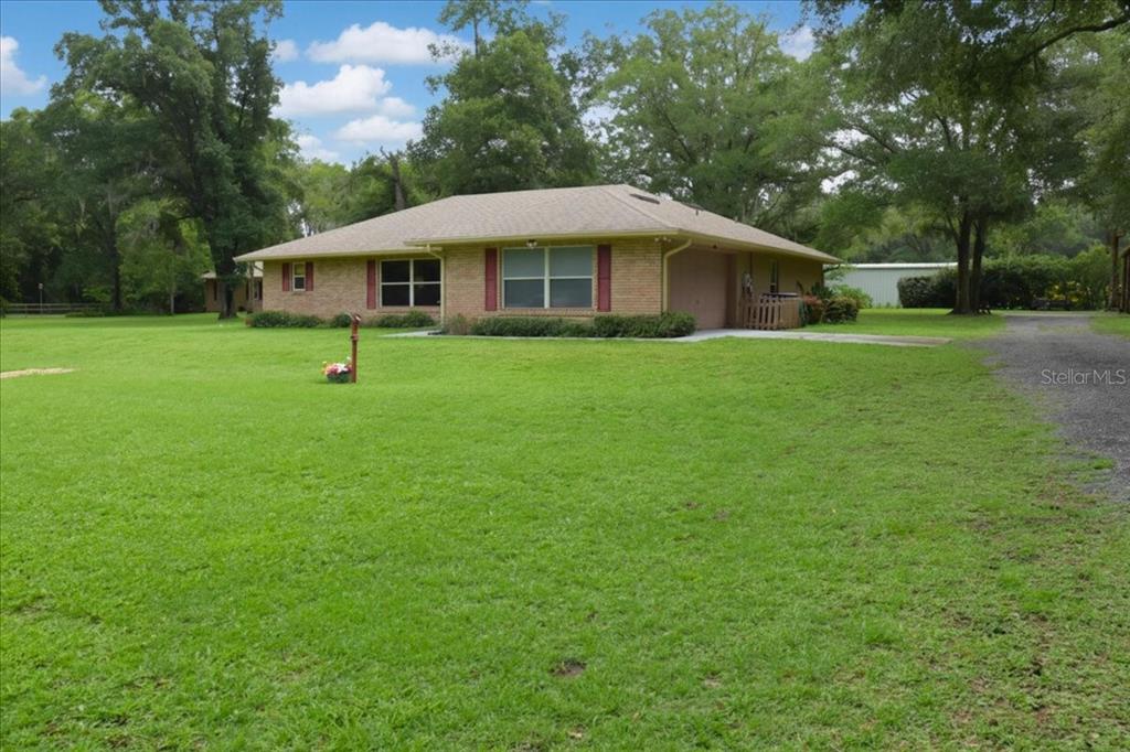 Full front elevation of this ranch-style brick home on acreage and long driveway.