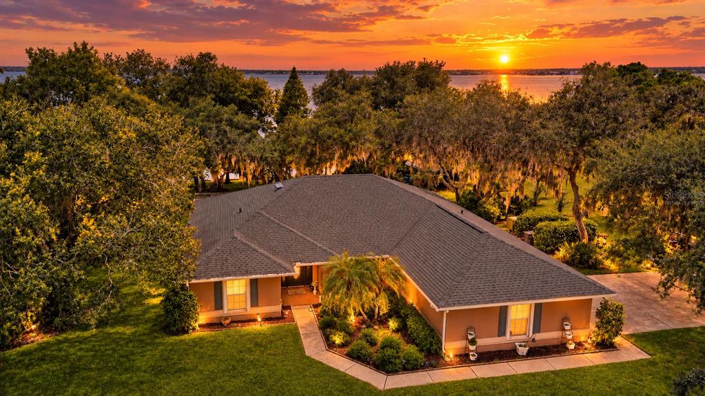 Beautiful view of the home, land, lake and sunsetVirtually staged
