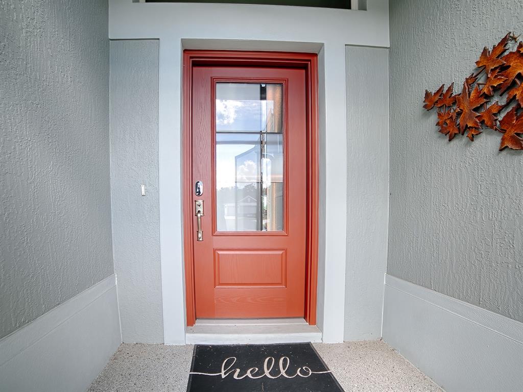 INVITING ENTRANCE WITH A DECORATIVE CONCRETE COATED ENTRANCE AND LEADED GLASS FRONT DOOR.