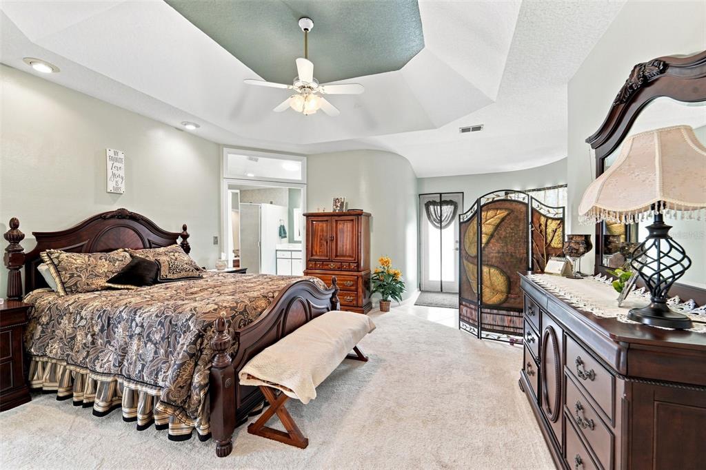 Large primary bedroom with ensuite bathroom, walk-in closet and a convenient sitting area near the pool deck entrance.