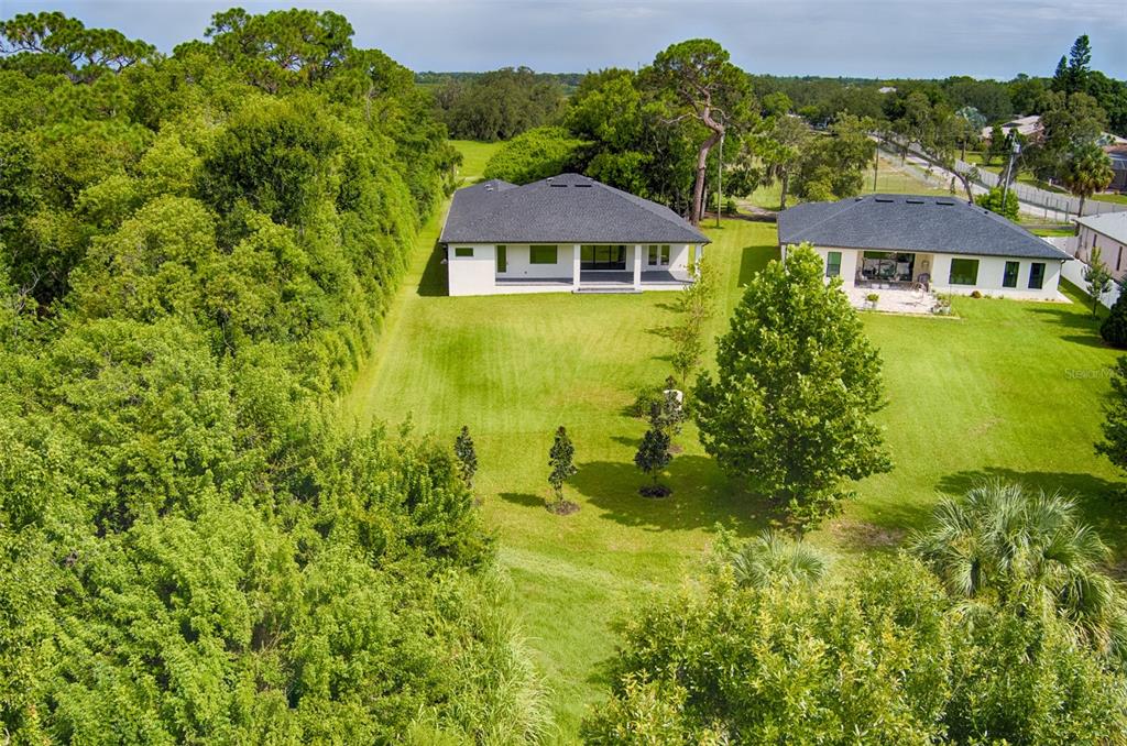 Aerial view of the expansive backyard, offering plenty of open green space and a peaceful, private setting surrounded by lush nature. Imagine adding a pool, a playground, an outdoor kitchen, or your own backyard oasis—the possibilities are endless!