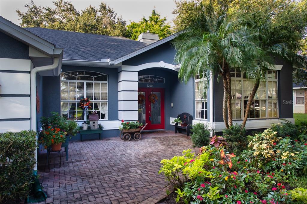 Spacious front paver patio with mature landscaping