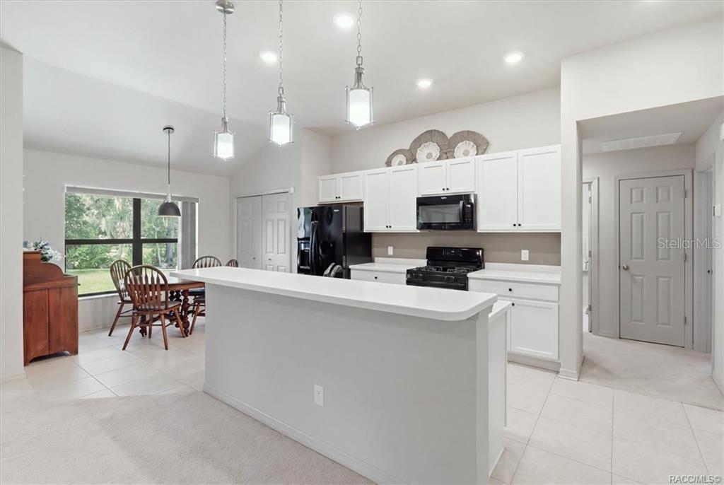 Kitchen w/ Breakfast Nook, White Cabinetry, Quartz Countertops, Black Appliances, Island w/ Raised Breakfast Bar & Pantry Closet