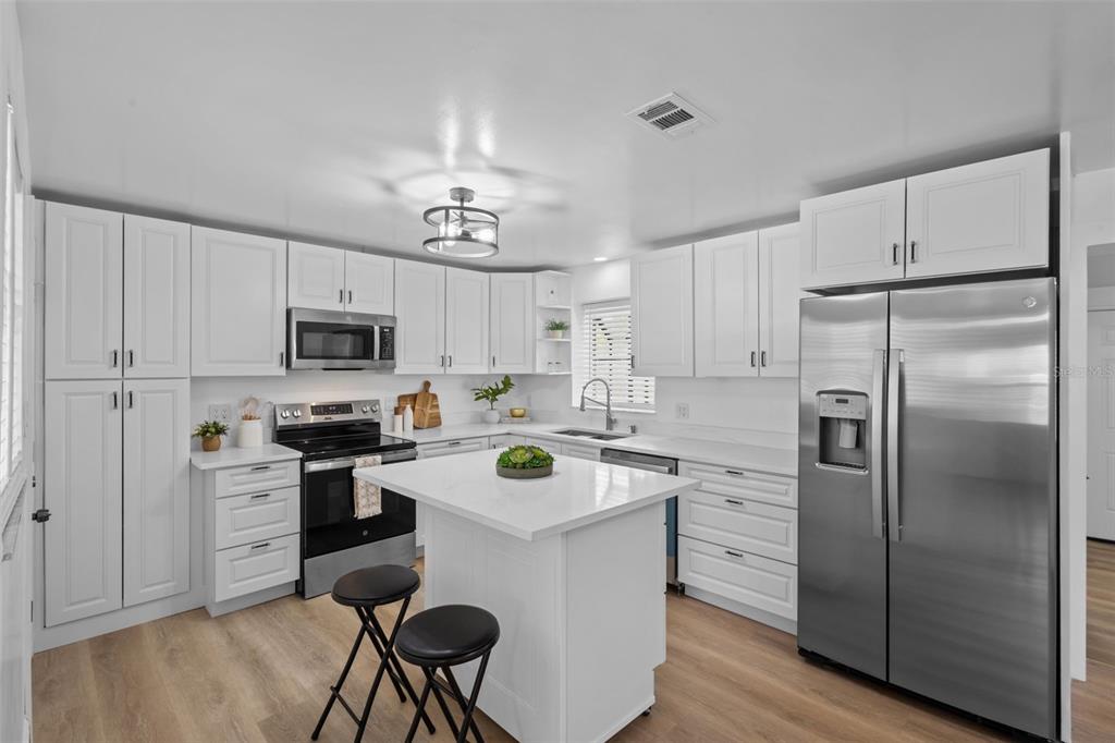 Completely remodeled kitchen featuring white shaker cabinetry, stone countertops, stainless steel appliances, and modern finishes.