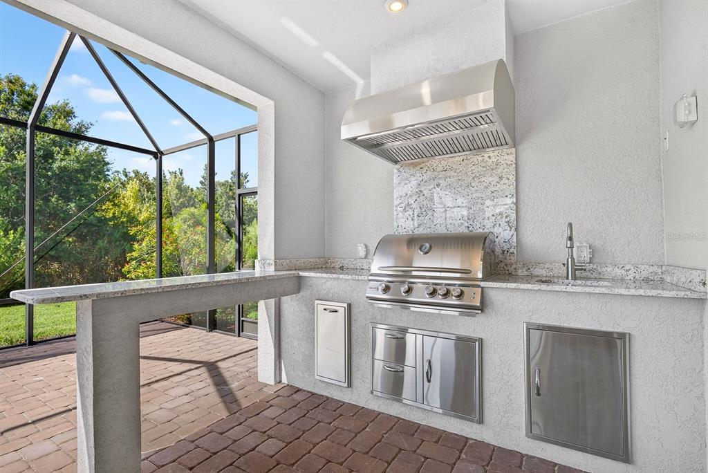 Outdoor kitchen with bar seating and a gas grill, perfect for entertaining!