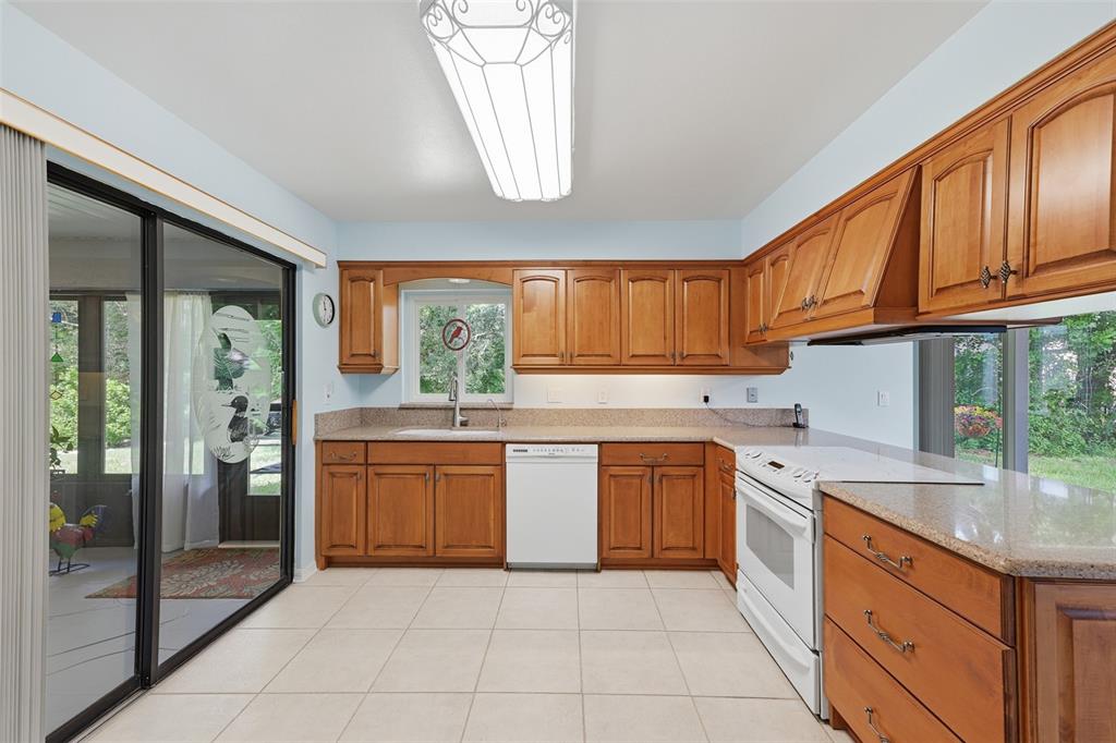UPDATED SPACIOUS KITCHEN WITH WOOD CABINETS, SOLID SURFACE COUJTER TOPS, SLIDE IN RANGE WITH CUSTOM HOOD.