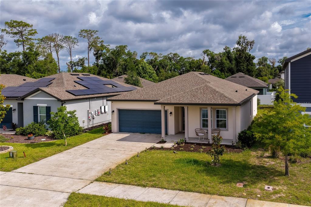 Angled aerial view highlighting the home’s architectural design, complete with a classic gabled roofline and an expansive front yard. The view also captures neighboring properties, emphasizing the community's clean and cohesive streetscape.