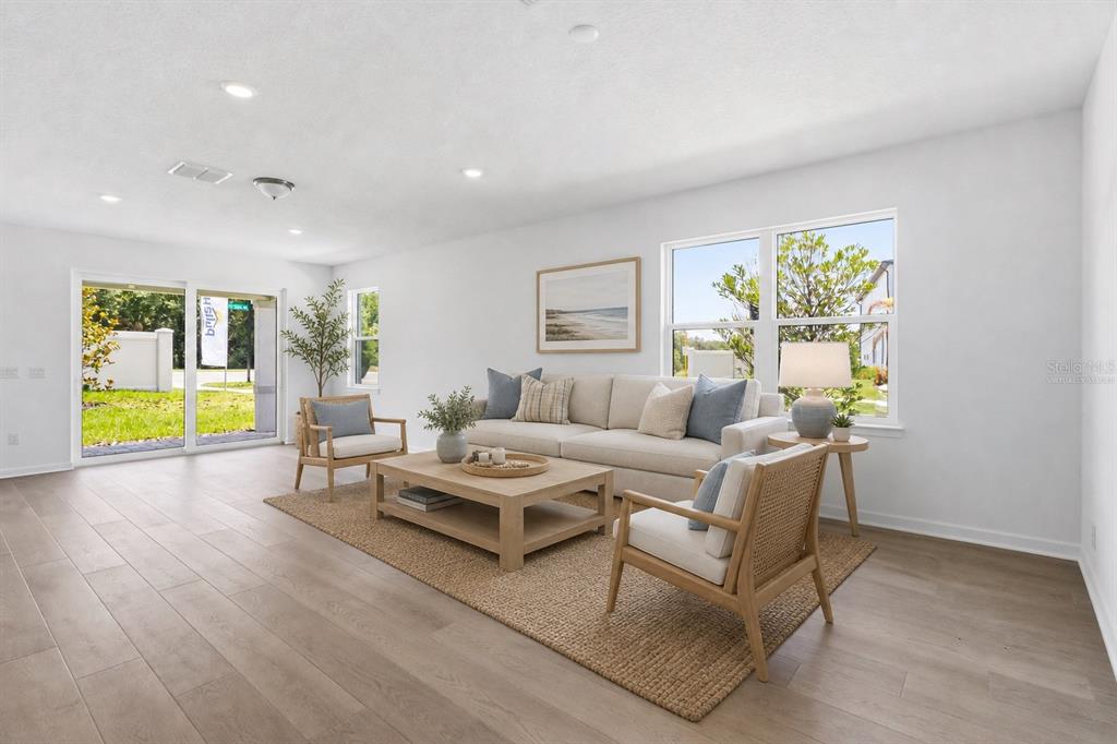 Virtually staged living space with warm wood look floors and an easy open layout.