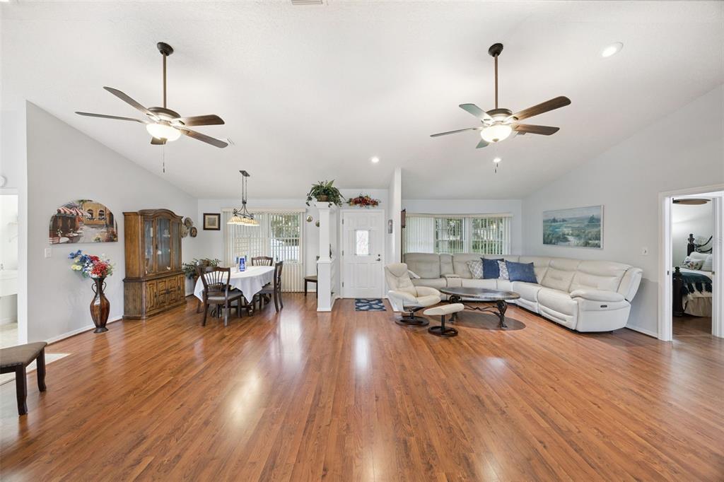 Open-concept great room (21x16) with vaulted ceilings, dual ceiling fans, recessed lighting, and laminate floors at 480 Lake Forest Cir, Mount Dora, FL