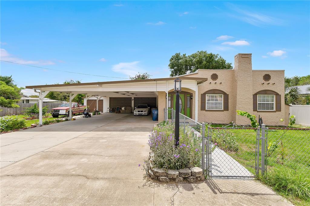 Charming curb appeal with inviting front porch, distinctive architectural details, attached garage, and oversized covered carport.