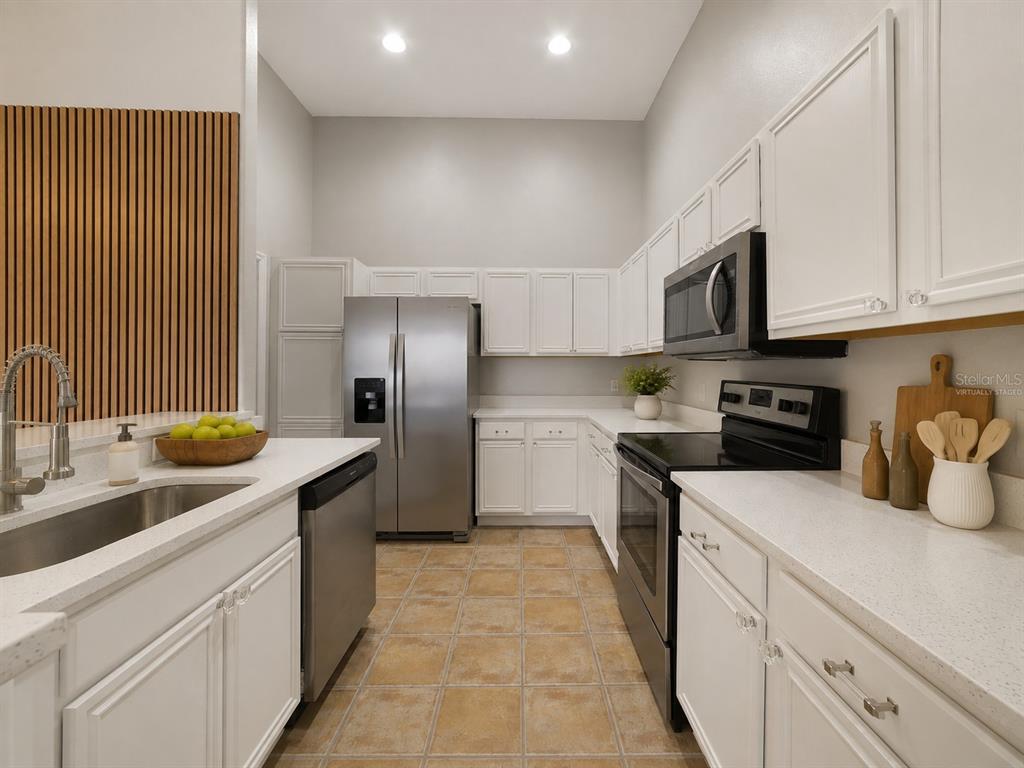 The UPDATED KITCHEN is truly the heart of the home, featuring abundant WHITE SOLID-WOOD CABINETRY, solid-surface countertops, STAINLESS STEEL APPLIANCES and a convenient BREAKFAST BAR for casual meals or entertaining. Virtually Staged