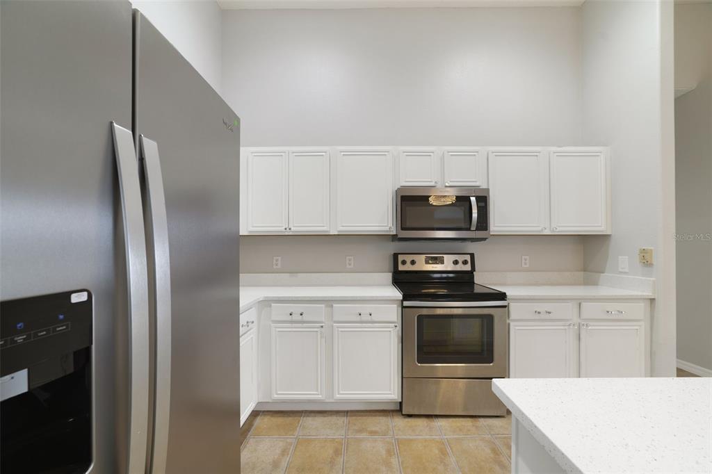 The UPDATED KITCHEN is truly the heart of the home, featuring abundant WHITE SOLID-WOOD CABINETRY, solid-surface countertops, STAINLESS STEEL APPLIANCES and a convenient BREAKFAST BAR for casual meals or entertaining.