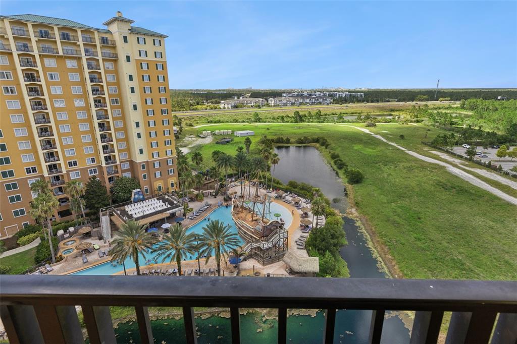 Balcony View | The private balcony offers expansive views of the pool, pond, and open green space beyond.