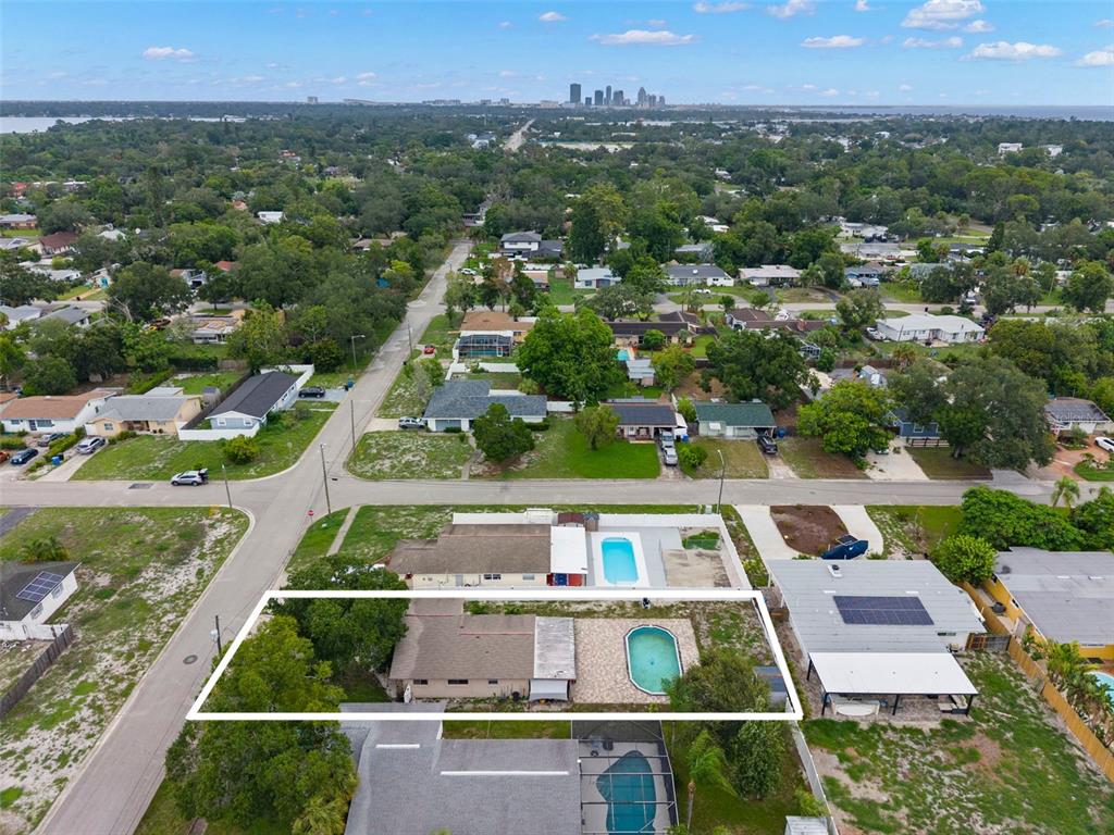 The aerial view of the outlined property showcases the home’s deep homesite, private backyard pool, and convenient location, with the Downtown St. Petersburg skyline visible on the horizon.