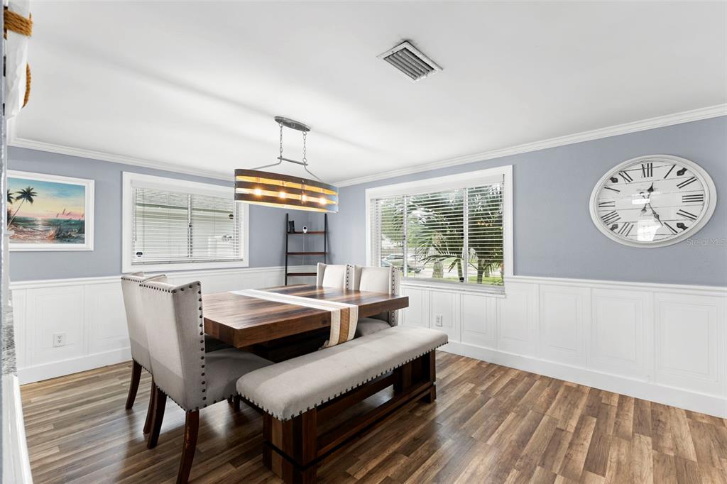 Two large windows fill the dining area with natural light, while crisp white millwork, soft gray walls, and warm wood tones give the room a polished, cohesive finish.
