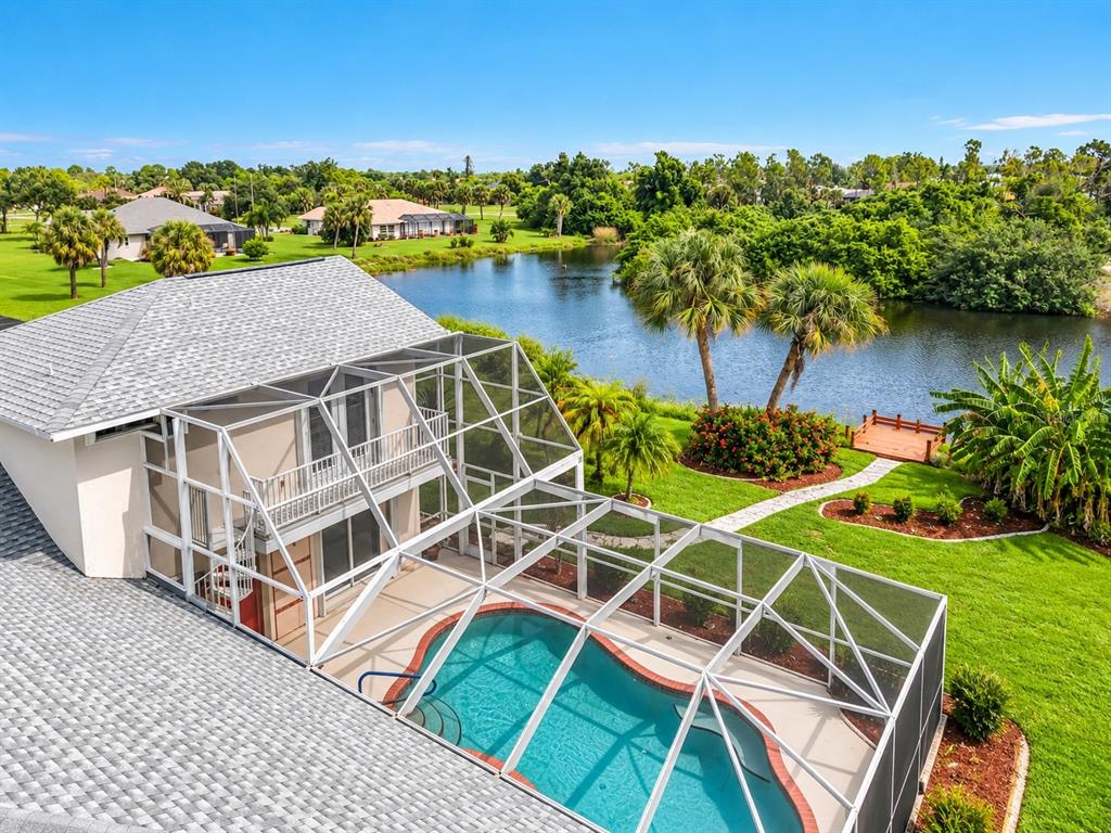 Aerial view of the home, screened pool, and pond