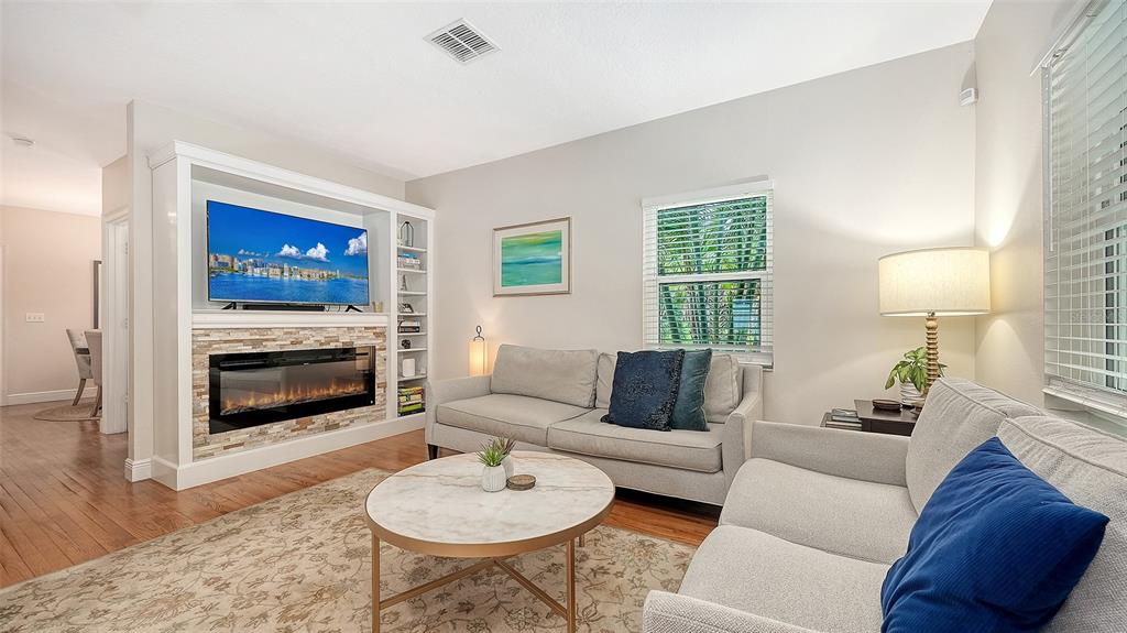 Expansive living area offers an inviting blend of comfort and luxury with hardwood flooring, fireplace, and abundant natural light.