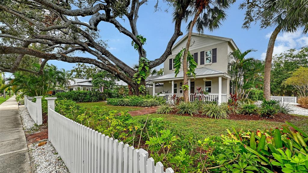 Elegant front elevation framed by a magnificent mature oak and lush tropical landscaping creates a sophisticated first impression.