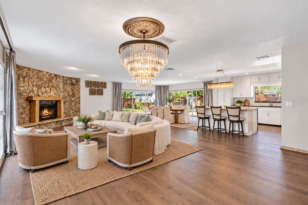 Virtually Staged. An open-concept layout is anchored by a striking floor-to-ceiling stone fireplace and wide plank wood-look flooring.