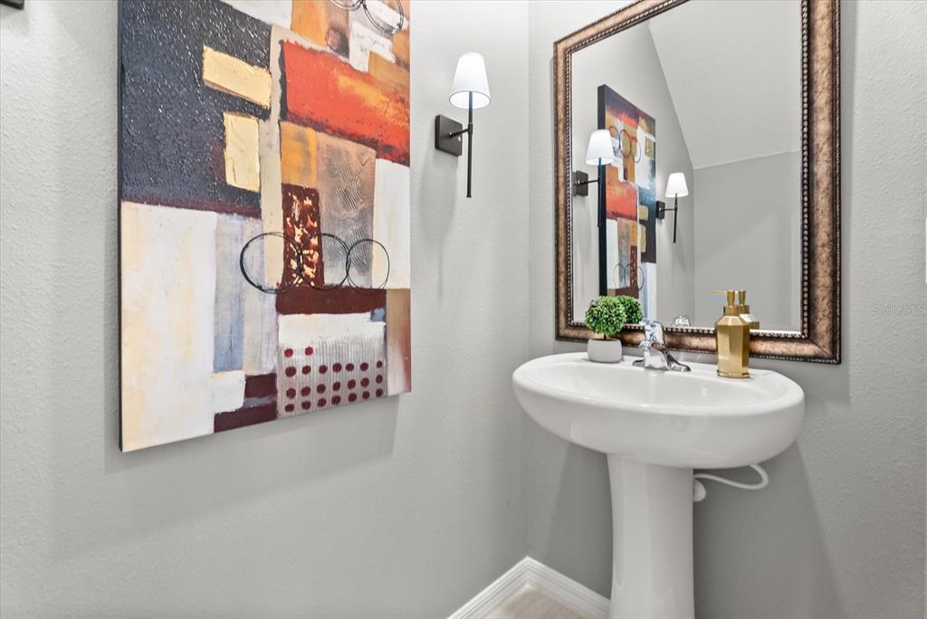 Stylish first-floor powder room with pedestal sink and framed mirror.