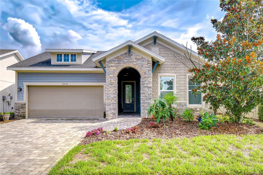 Beautiful David Weekley "Lorenzo" model with charming architectural details, paver driveway, manicured landscaping, and a rare three-car tandem garage with built-in storage.