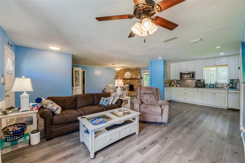 Bright open-concept living area with LVP flooring, cool blue walls, and a ceiling fan leading into the adjacent kitchen and dining spaces.