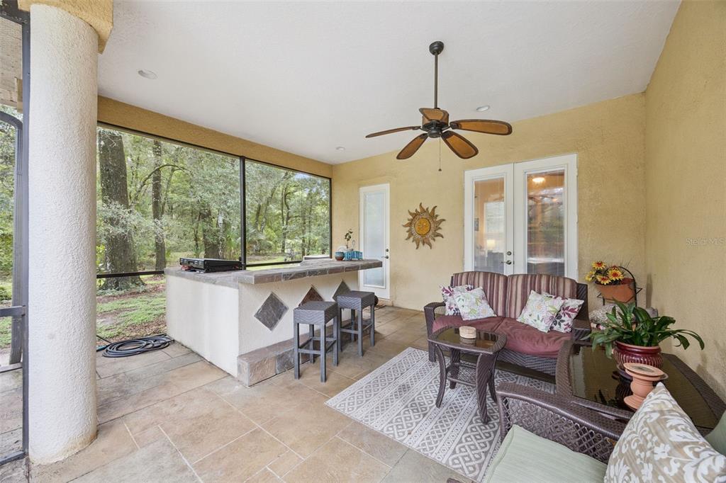 Covered lanai with outdoor kitchen makes entertaining by the pool easy year-round. A perfect spot for evening entertaining with friends.