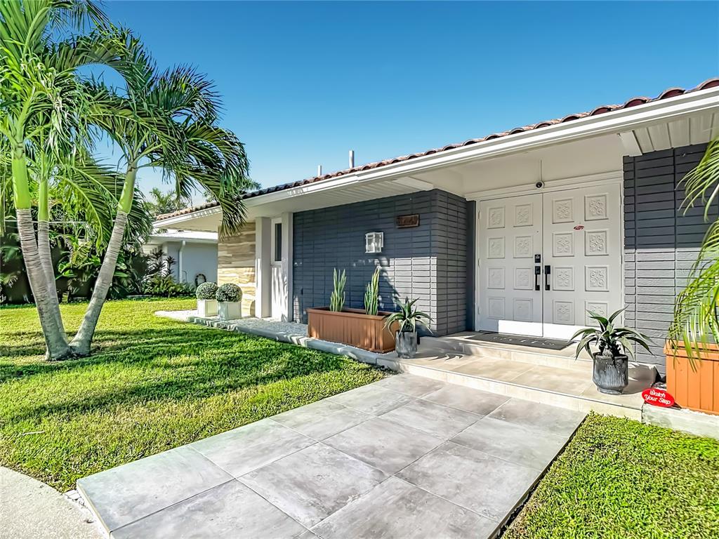 Front Exterior – Welcoming front exterior featuring a contemporary entrance, attached garage, mature palm trees, and landscaped front yard.