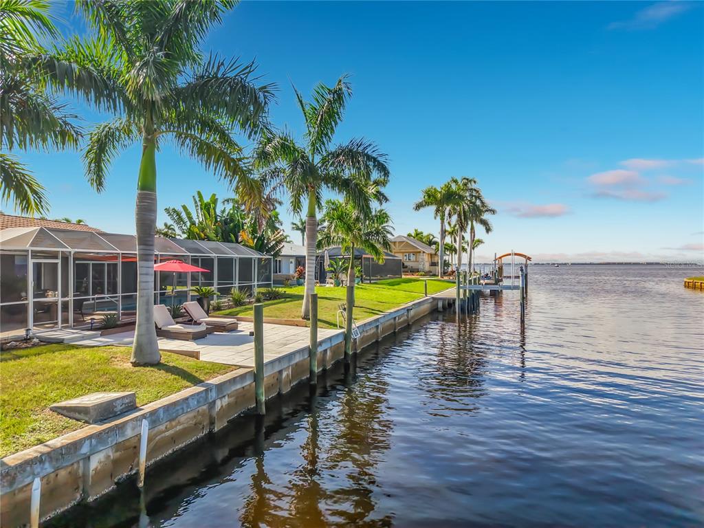 Waterfront & Seawall – Waterfront view from the property showcasing the canal, seawall, tropical landscaping, and open-water setting.