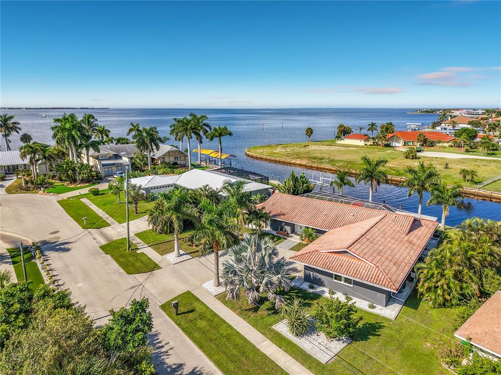 Aerial View – Aerial view showcasing the waterfront property, surrounding neighborhood, canal, and expansive water beyond.