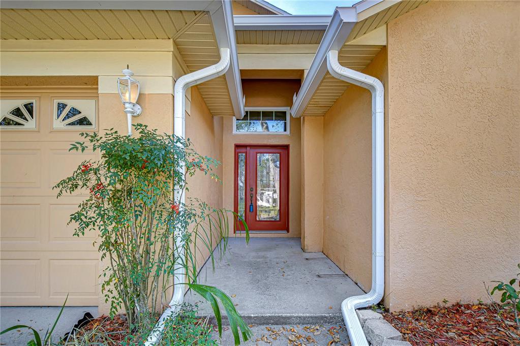 Inviting covered entryway featuring a bold red front door and charming exterior details.