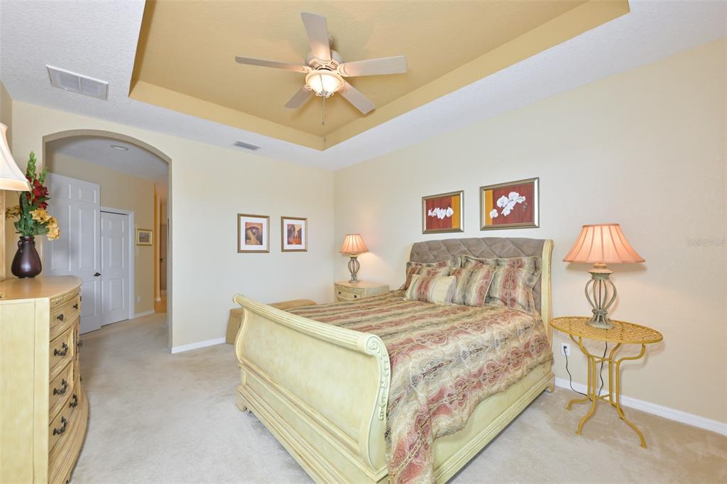 Main bedroom with trey ceiling, tastefully decorated furniture, sleigh bed, dresser, side tables and lamps.