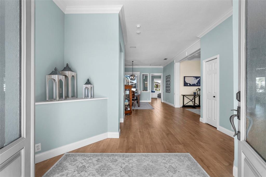 A welcoming entry with soft coastal colors, crown molding, and warm engineered flooring sets the tone for the home.